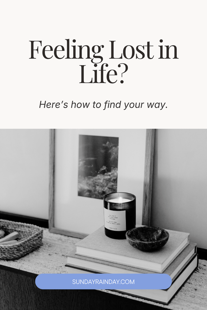Black and white photo of a candle and stacked books on a table beside a framed print, titled Feeling Lost in Life? Here's how to find your way