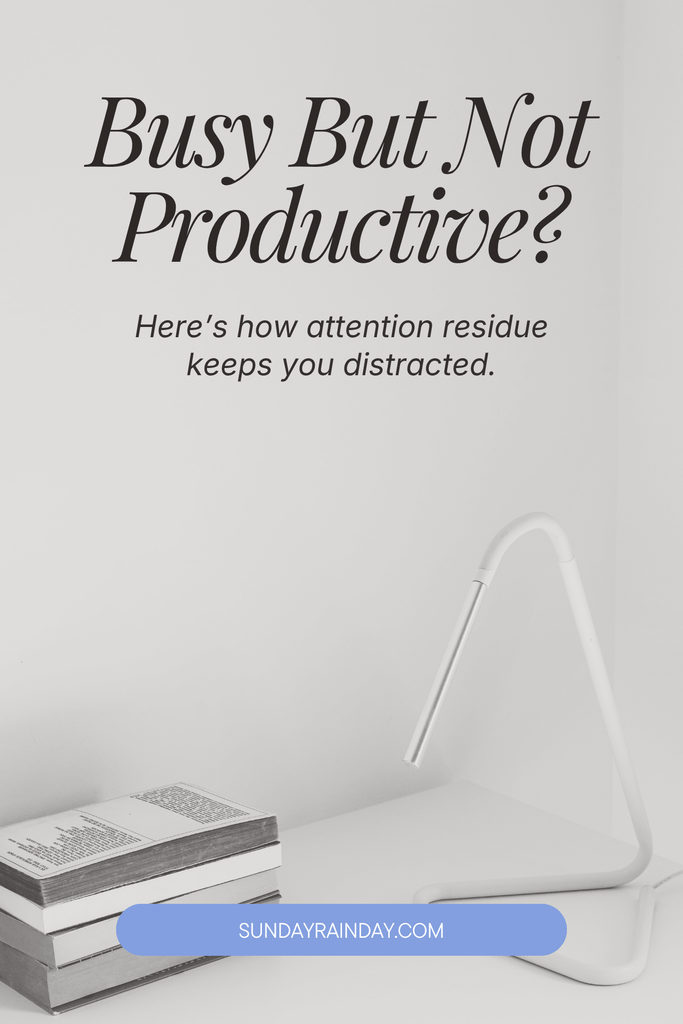 Busy but not productive — how attention residue keeps you distracted, on a minimalist black-and-white desk with books and a lamp.