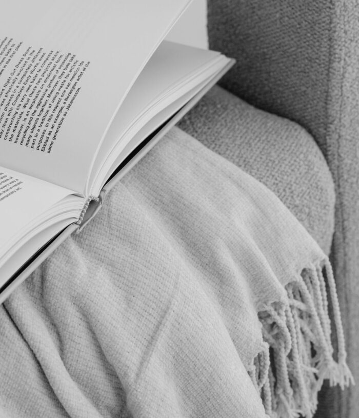 Black and white photo of an open book resting on a fringed throw over the arm of a sofa, for the Life Planning section